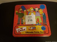 Metal game box lid with Simpsons characters and title shown