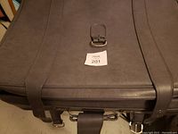 Top exterior view of a large gray suitcase with a buckle and leather-like straps.