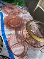 Various pink Depression glass plates and serving dishes arranged on a table.
