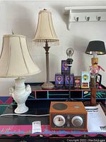 Full view of lamps, lamp shades, novelty bulbs, and clock radio on table