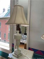 Full view of marble base table lamp with fabric shade on window sill showing overall shape and details