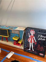 Photo showing the overall school-themed carrying case with miniature desk, blackboard and labeled box.