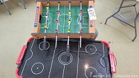 Foosball table on top of air hockey table with visible players and handles