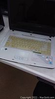 White Acer Aspire 5710 laptop with visible wear and yellowed keyboard, screen off.