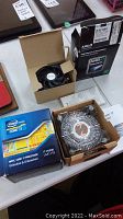Photo of both boxed processors and included cooling fans from a top-side view showing Intel Core i7 and AMD Phenom II packaging on table.