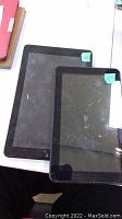 Two tablets side by side showing front screens with wear and smudges.