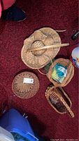 Top view showing four wicker baskets and a pair of gardening gloves on carpeted floor.