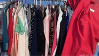Front view of assorted ladies dresses and blouses hanging on a clothing rack featuring a variety of colors and materials