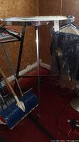 Photo shows a retail clothing rack with chrome frame and white circular top, some wear visible including scratches and adhesive remnants.