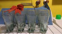 Frontal image showing all 8 Coca-Cola glasses neatly placed in the metal wire carrying tray with handle.