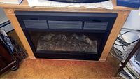 Electric fireplace insert showing oak finish frame and vents on top.