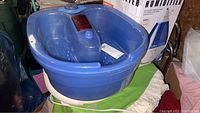 Blue feet massager and foot bath pan on white base, placed in basement storage area
