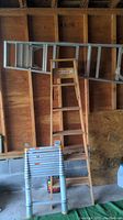 Photo showing the 6 ft aluminum ladder, 6 ft wooden ladder, and 12 ft telescopic aluminum ladder standing against a wooden wall in a garage.