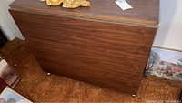 Closed view of the wooden drop leaf table showing the wood grain finish and compact folded size.