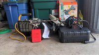 Photo showing Makita 18V cordless drill, Black & Decker saw and drill, Coleman drill, work light and heat device light on garage floor