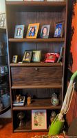 First bookshelf with drop-front secretary, framed photos, and red rotary phone. Shows some scratches and wear.