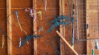 Photo showing four wire garden trellises and wire tray against garage walls with some tied colored strings