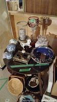 Photo showing table with various decorative balls, candle holders, music box, miniatures, and a footed bowl.