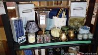 Photo of shelf with candle holders, candles, decorative vase, and various small decorative items arranged
