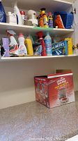 Photo of laundry room shelves with multiple cleaning products and the boxed Ultimate Spin Mop on the floor.