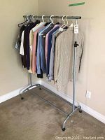 Full view of metal clothing rack holding nine pieces of women's clothing including sweaters and jackets in various colors.