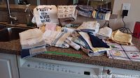 Photo showing assorted linen towels, cloth napkins, pillow case, and apron spread on a kitchen counter.