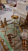 Pair of brass wall sconces and two candle holders shown on a glass table with a label indicating lot number 320