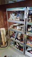 Metal shelving unit loaded with various items showing structure and shelf material in basement setting.