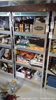 Metal shelving unit with press board shelves placed in basement, filled with various items not part of lot.