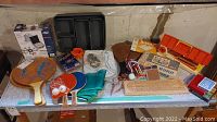 Full view of untested various gaming items on a table, including paddles, boards, trays and cards
