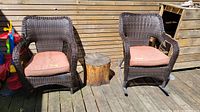 Both outdoor wicker rocking chairs placed side by side with cushions on a wooden deck, showing overall condition and color.
