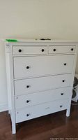 Front view of white 6-drawer dresser showing two small upper drawers and four larger drawers beneath.