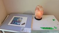 Print and salt lamp displayed on a white table, showing lamp's color and crack, and print in protective sleeve.