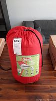 Red Coleman sleeping bag in compression sack with label visible
