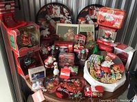 Wide view of the lot showing various Coca-Cola Christmas collectibles including trays, figurines, ornaments, miniature bottles, toy truck and a holiday puzzle.