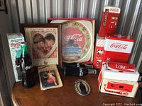 Full view of Coca-Cola vintage collectibles including bottle-shaped radio/camera, wallplates, signs, and miniature vending machine