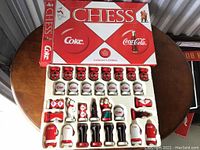 Full chess set with pieces arranged in their tray and the collectible box lid displayed behind showing 'Chess', Coke logo and bottle images.