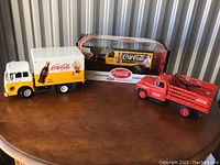 Set of three Coca-Cola branded die-cast model trucks with one in original packaging.