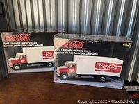 Two Coca-Cola Ford Louisville Delivery Truck model kits, one opened and one still sealed in plastic.