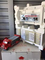 Die-cast metal 1938 Coca-Cola delivery truck model displayed alongside white foam packaging revealing boxed parts and manufacturer's printed details on the box.