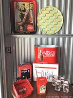 Full view of Coca-Cola collectible set including two metal trays, cooler bucket, ice bucket, tin containers, ashtray holder, and six glasses.