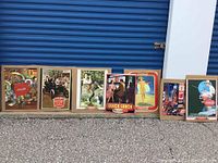 A group of six completed Coca-Cola puzzles leaning against a wall, showing various vintage advertising art.