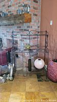 Front view of metal bakers rack with decorative glass and ceramic vases.