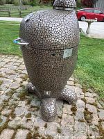 Front view of Komodo ceramic kamado grill on pebble mosaic exterior standing on molded feet