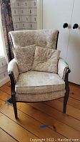 Front view of vintage upholstered armchair with two matching accent pillows on seat.