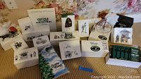 Overview of assorted Dept. 56 Heritage Village miniatures in original boxes including buildings and figurines.