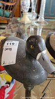 Close-up photo of Ray Pomeroy duck decoy showing head and yellow eye detail on black painted wooden body.