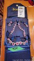 Full view of Stauer set in blue satin case showing sterling silver necklace and matching earrings with red stones surrounded by clear stones, marked 925 sterling silver.