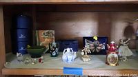 Shelf view showing whole lot: Swarovski boxes, crystal figurines, green bowl, glass shot glass, decorative boxes, and ballerina figurine