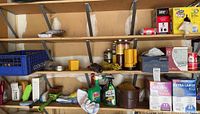 Wide view of three shelves with assorted barbecue items, propane tanks, rags, plumbing hardware, automotive cleaning items, and trash bags arranged on and above shelves.